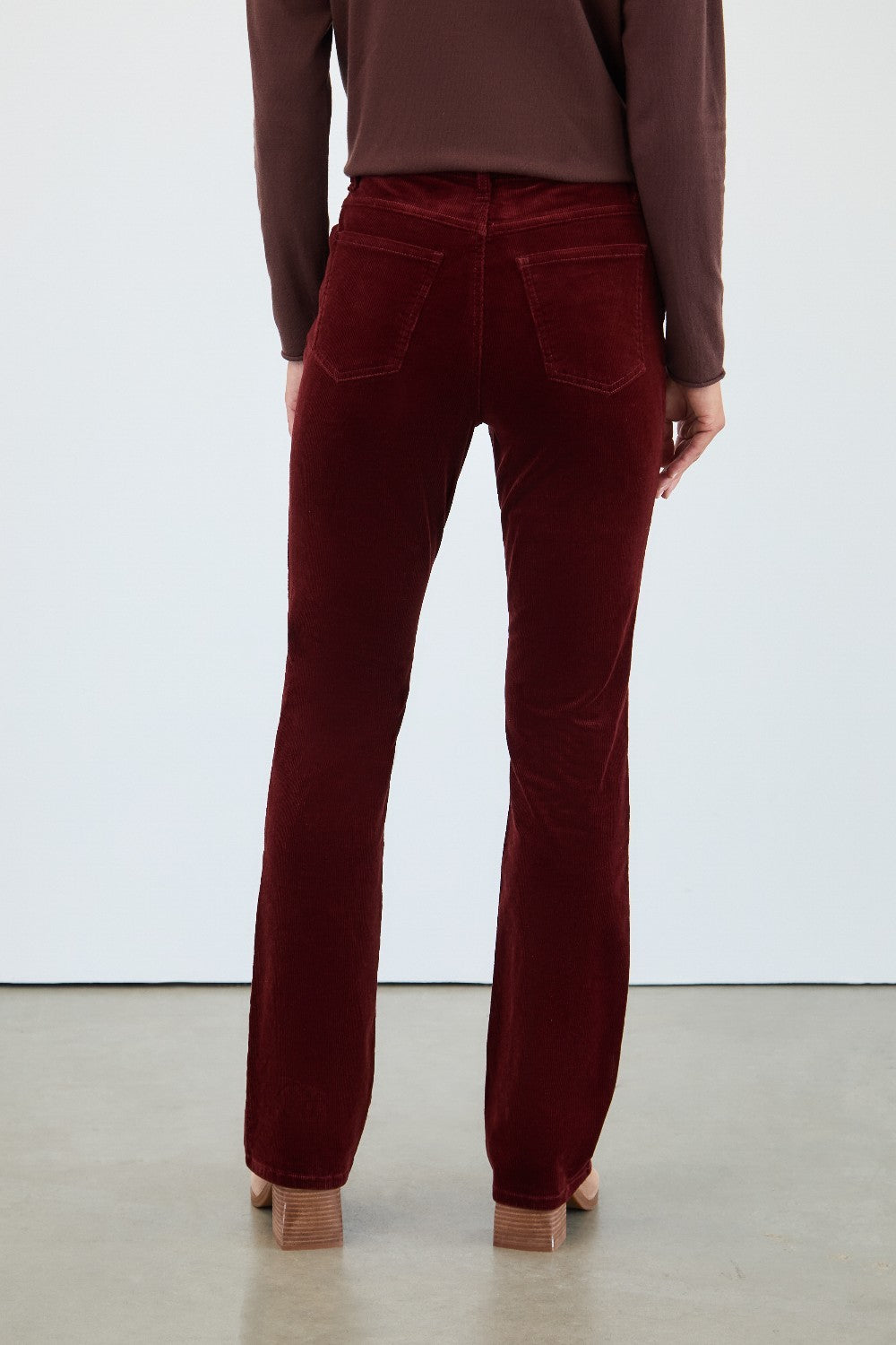 Maroon velvet pants worn by a person on a white background