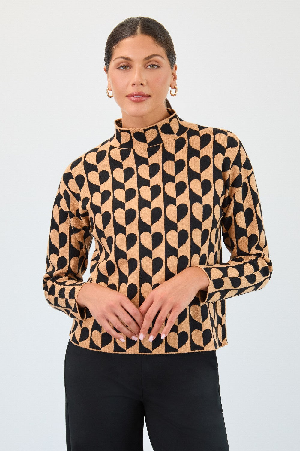 Woman wearing a patterned top with black and beige design on a plain background