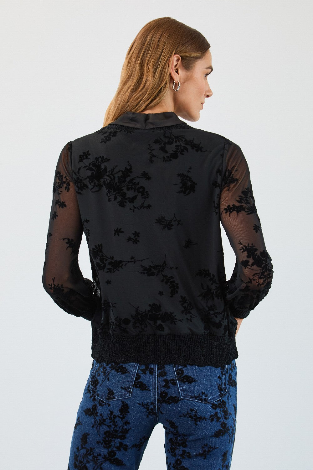 Woman wearing a black top and blue pants with a white background