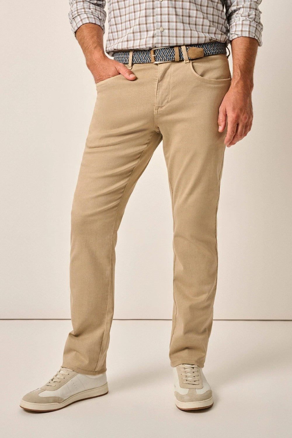 Person wearing beige pants and a plaid shirt on a plain background