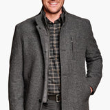 Man wearing a gray coat over a plaid shirt on a white background