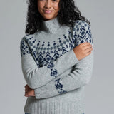 Woman wearing a gray sweater with patterned sleeves against a plain background