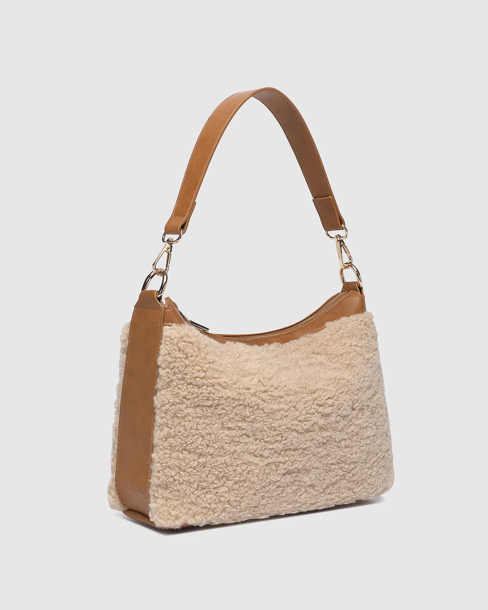 The Louenhide Aspen Shoulder Bag is the soft-structured silhouette your winter wardrobe’s been waiting for. Crafted in a faux shearling texture with warm neutral tones, this sherpa bag brings a subtle warmth to cool-weather dressing. Light gold hardware adds a refined touch to this beige shoulder bag, while the spacious interior easily fits your daily essentials. Whether styled with denim or layered with flowing silhouettes, the Aspen is designed to move with you through the season - statement, elevated, an