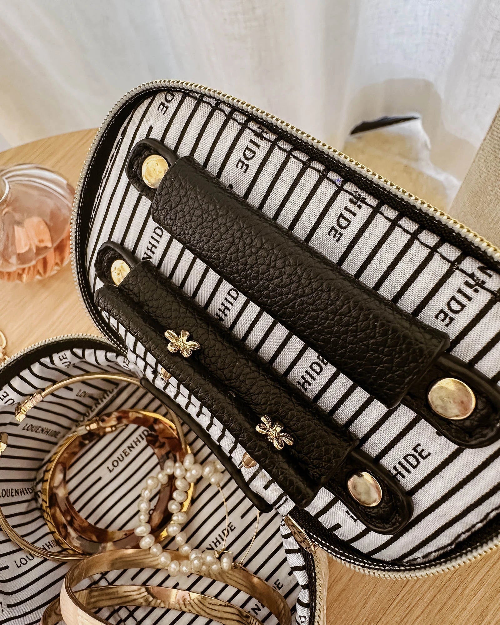 The Louenhide Trudy Jewelry Box is the perfect solution to keeping your valuables safely organized on the go. This compact travel jewelry case fits seamlessly into your luggage without taking up space. The secure zip closure ensures your jewelry stays protected, while the textured raffia and contrasting faux leather exterior add a touch of understated luxury to your travel style.