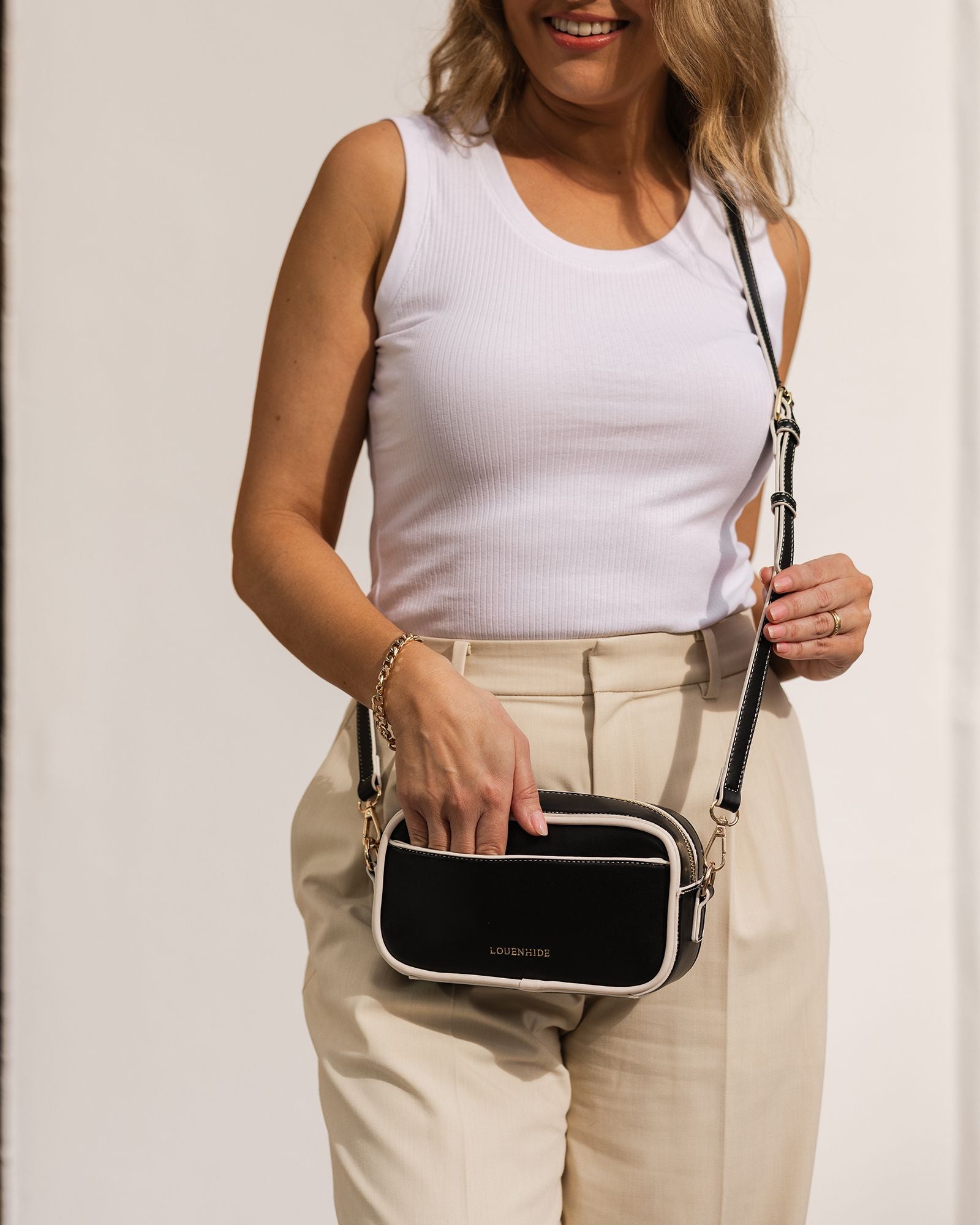 The Louenhide Xanadu Crossbody Bag is the ultimate cool girl accessory for summer. With white contrast trimming, this new camera bag styles is a fun way to embrace the season with a burst of brightness! Allowing you to completely customise your look, the Xanadu features two ways to wear. Simply attach the adjustable vegan leather strap to complement your everyday style or interchange the shorter shoulder strap with light gold chain detailing to elevate your evening attire.