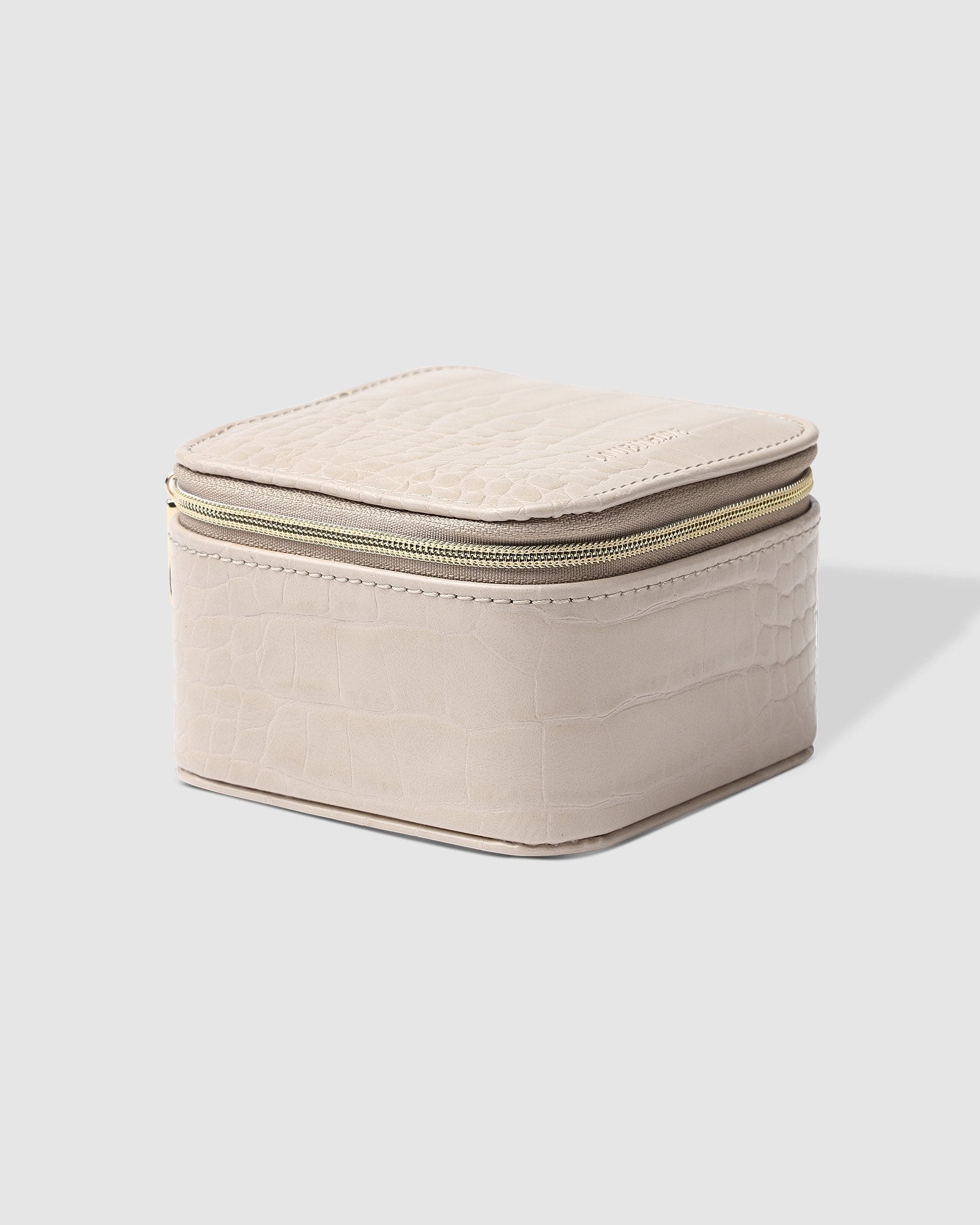 The Louenhide Beau Jewelry Box is a small, square jewellery organizer designed to keep your pieces safe and secure at home or when you are on the go. Featuring a vegan croc exterior, the Beau is every woman's dream jewelry case! Store your larger pieces in the main compartment, while safely stowing your smaller jewels in the elasticated slip pocket