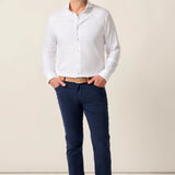 Man wearing a white dress shirt and navy pants against a beige background