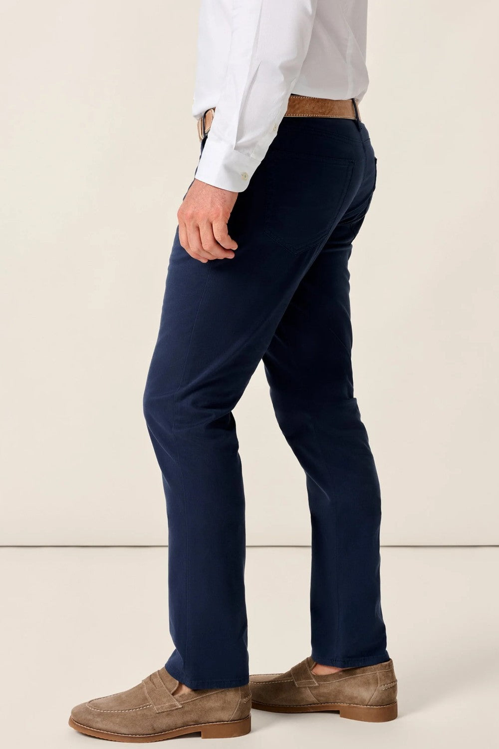 Person wearing navy pants and a white shirt with a beige background