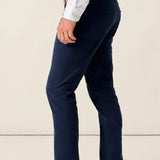 Person wearing navy pants and a white shirt with a beige background