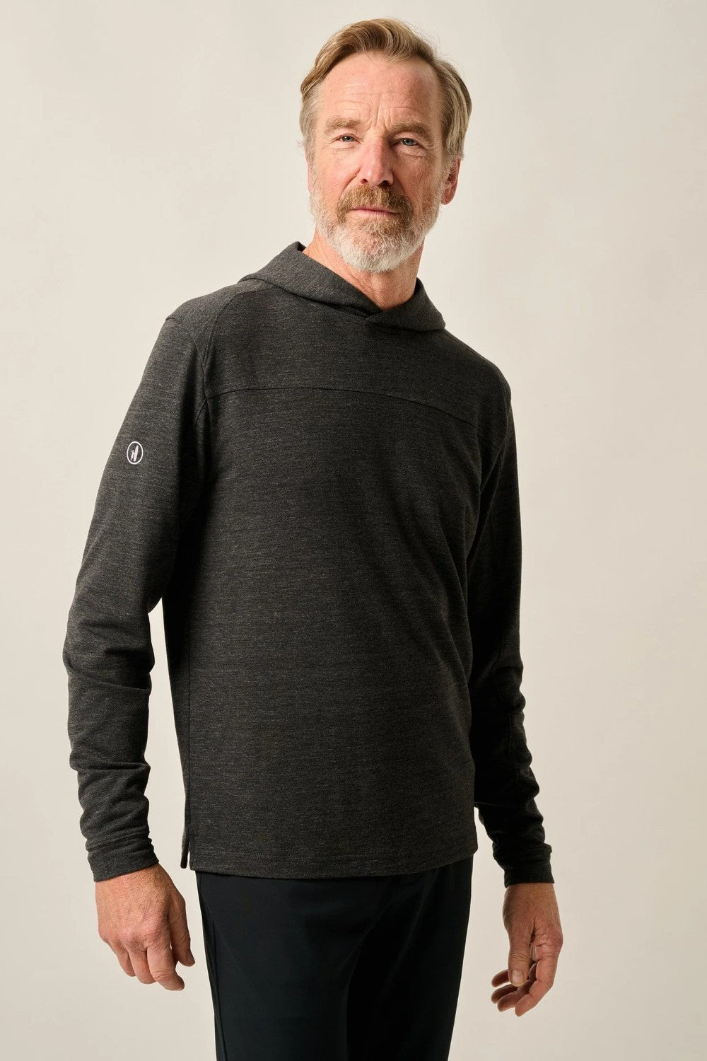 Man wearing a dark gray long-sleeve shirt with a hood against a plain background