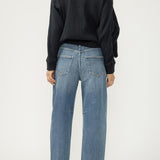 Person wearing blue jeans and a black sweater on a white background