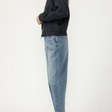 Person wearing a dark sweater and light blue jeans on a white background