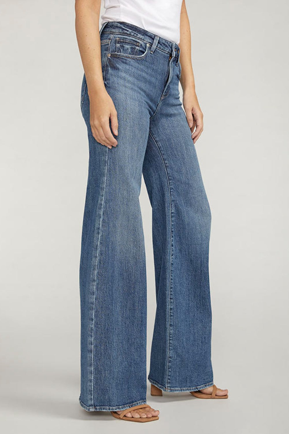 Person wearing blue jeans on a plain background