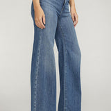 Person wearing blue jeans on a plain background