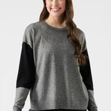 Woman wearing a gray sweater with black sleeves on a white background