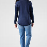 Woman wearing a navy long-sleeve top and light blue jeans on a white background