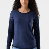 Woman wearing a navy long-sleeve shirt and light blue jeans on a white background