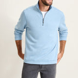 Man wearing a light blue pullover with a zipper on a plain background