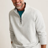Man wearing a light gray pullover with a zipper, smiling against a plain background
