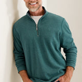 Man wearing a teal pullover with a zipper, standing against a plain background