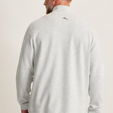 Man wearing a light gray long-sleeve shirt with a small logo on the back against a plain background