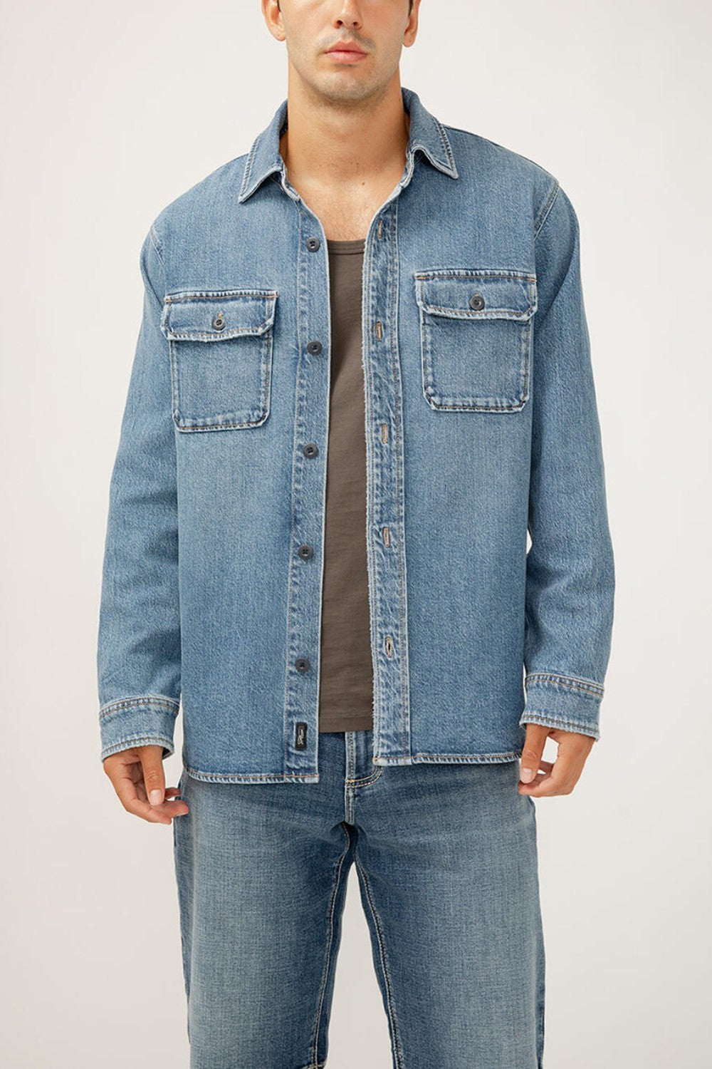 The perfect layer for any season? A men's denim shacket. This stylish top layer combines the structure of a jacket with the ease of a shirt, featuring a relaxed fit and oversized pockets. Wear it open or buttoned up, this jean shacket is sure to be your new staple layer.