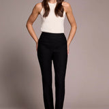 Woman wearing a white sleeveless top and black pants against a neutral background