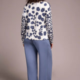 Person wearing a patterned top and blue pants against a beige background