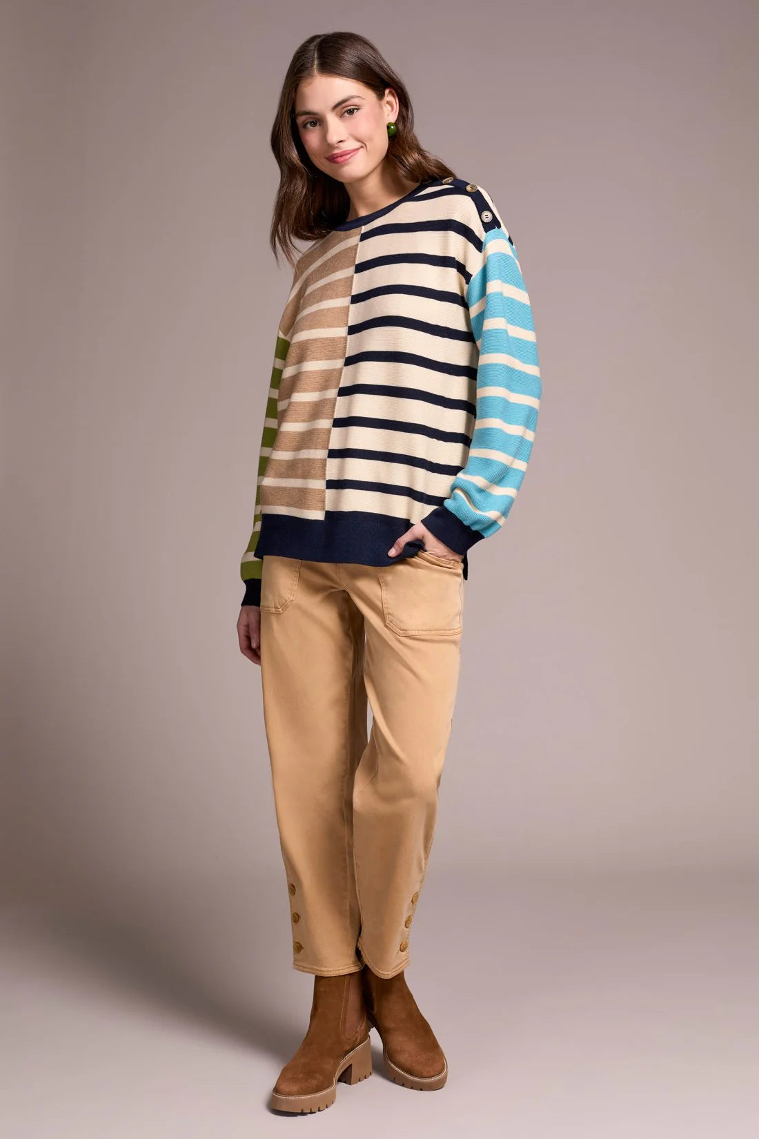 Woman wearing a striped sweater and beige pants against a plain background