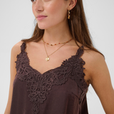 Close up of a woman modelling a brown camisole with lace detail at neckline photographed against a light backdrop.