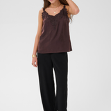 Woman modelling a brown camisole with black pants and black shoes photographed against a light backdrop.