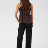 Woman, shown from behind, modelling a brown camisole with black pants photographed against a light backdrop.