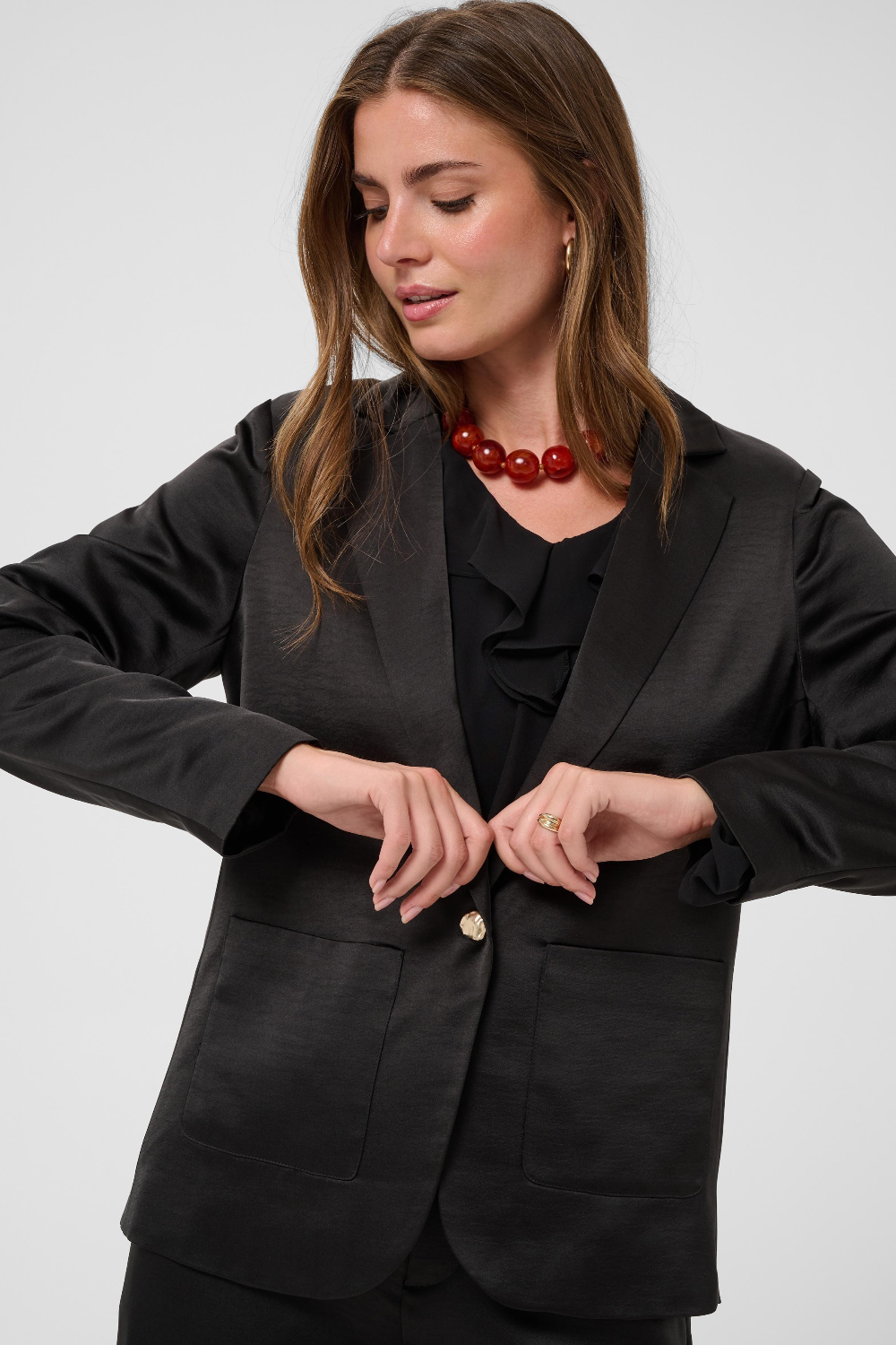 Women modelling a black sateen suit with a black blouse photographed against a light background.