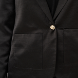 Close up of a black sateen suit with a black blouse photographed against a light background.