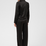 Women, shown from behind, modelling a black sateen suit with black kitten heels photographed against a light background.