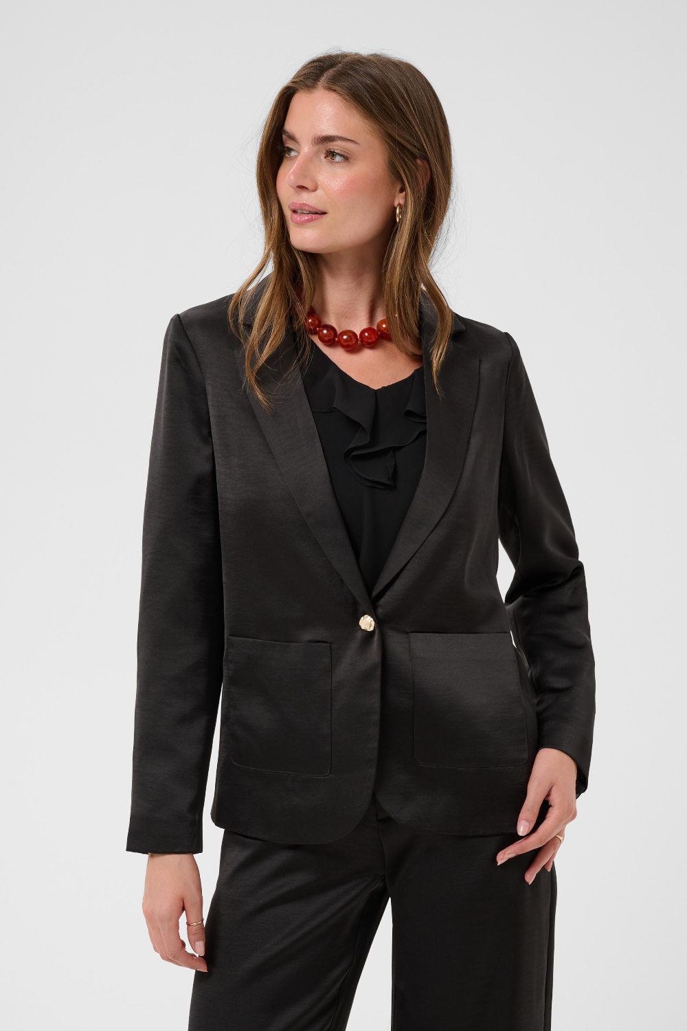 Women modelling a black sateen suit with a black blouse photographed against a light background.