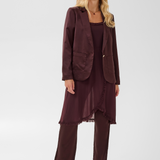 Woman modelling a deep wine coloured sateen blazer with a matching top and pant, and black kitten heels, photographed against a light background.