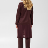 Woman, shown from behind, modelling a deep wine coloured sateen blazer with a matching top and pant, and black kitten heels, photographed against a light background.