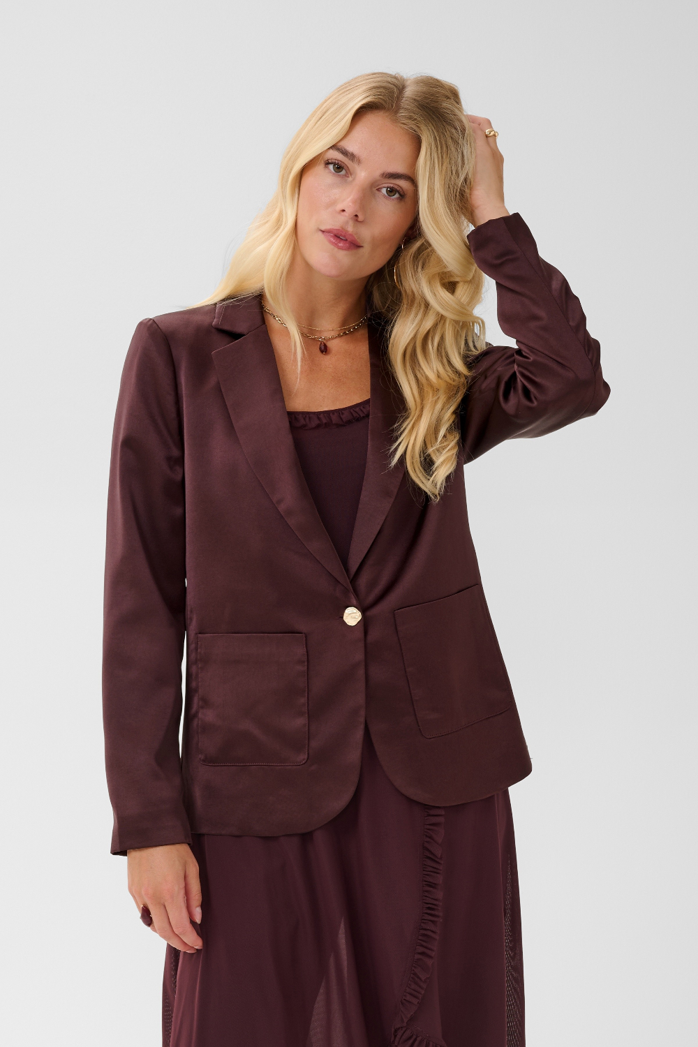 Woman modelling a deep wine coloured sateen blazer with a matching top and pant photographed against a light background.