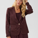 Woman modelling a deep wine coloured sateen blazer with a matching top and pant photographed against a light background.