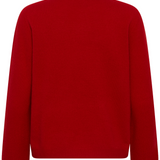 Back of a red turtle neck sweater photographed against a light backdrop.