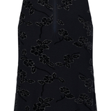 Back of a sleeveless embellished black top photographed against a light background.