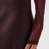 Close of of a woman modelling a deep wine coloured sateen skirt with a mesh top photographed against a light background.