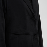 Close up of a woman modelling a black velour blazer with a sparkly black top photographed on a light background.