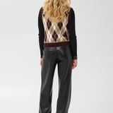 A model viewed from the back wearing a black long-sleeve top under a brown, beige, and black argyle sweater vest, paired with black faux leather wide-leg pants and black heels, on a light gray studio background.