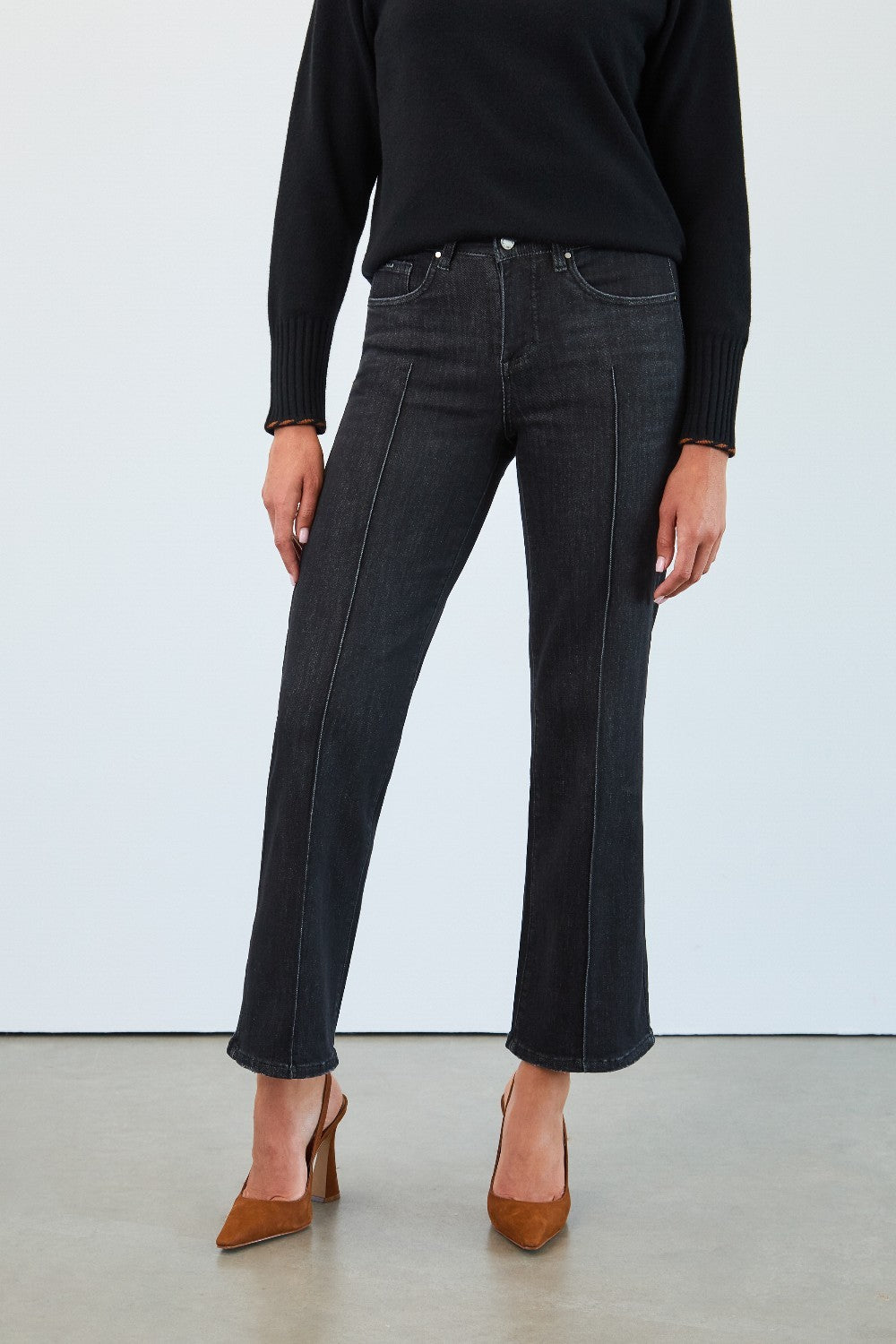 Person wearing black jeans and a black top against a white background