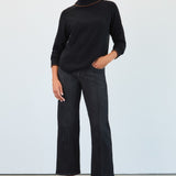 Person wearing a black turtleneck and dark jeans against a white background