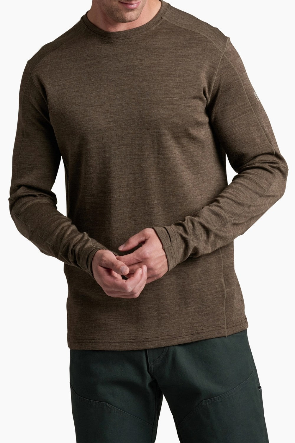 Man wearing a brown long-sleeve shirt and dark pants on a white background
