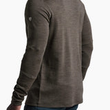 Man wearing a brown long-sleeve shirt with a small logo on the chest against a white background