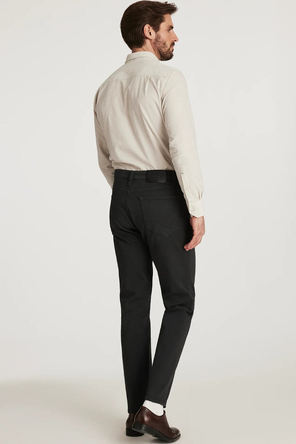Man wearing a beige shirt and charcoal pants on a white background